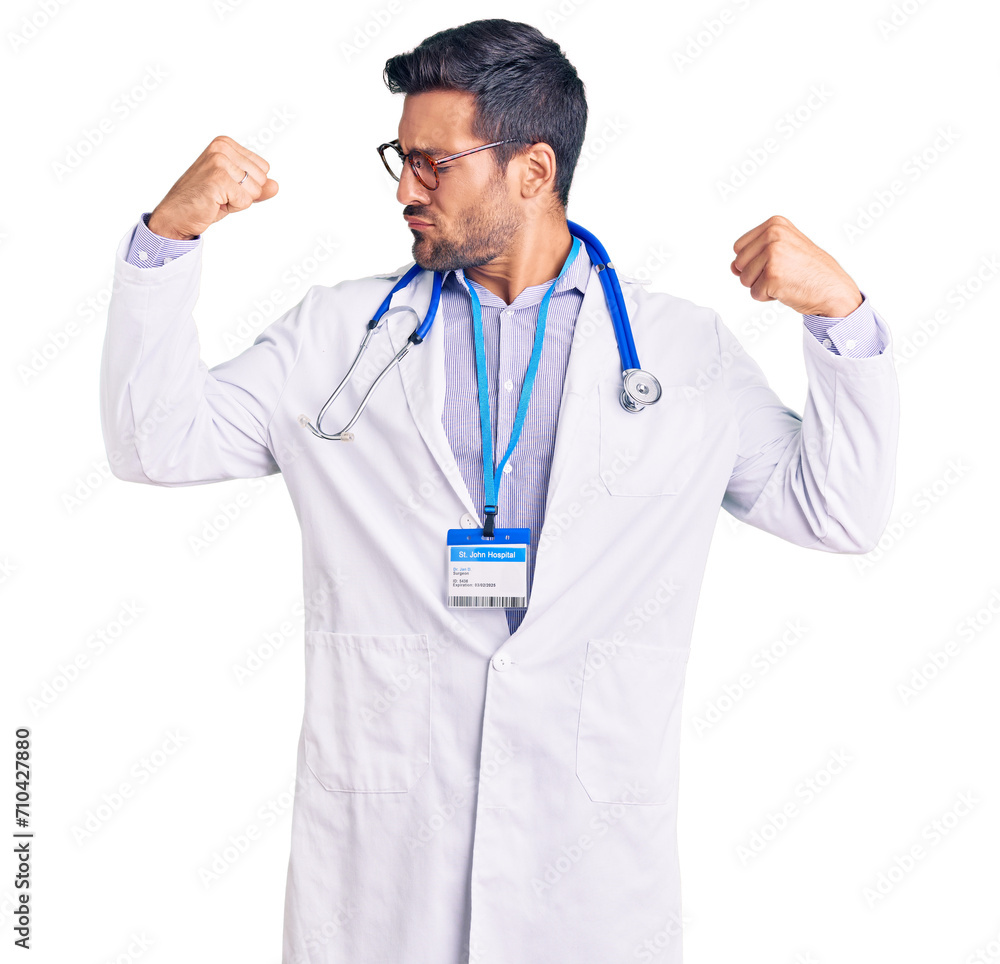 Young hispanic man wearing doctor uniform and stethoscope showing arms muscles smiling proud. fitness concept. Young hispanic man wearing doctor uniform and stethoscope showing arms muscles smiling proud. fitness concept.
