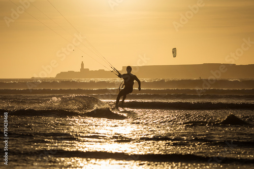 Silhouette of kitesurfer on the beach with reflection at sunset in background. Essaouira, Morocco