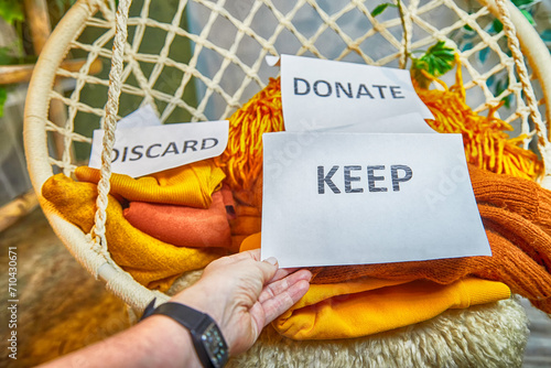 Photography Signs with the words keep, donate, discard and fashion clothes folded in stacks in cozy room