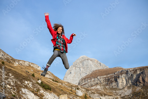 Joyful Mid Adult Woman Showing Her Vitality in a Athletic Funny Jump in the Air of Mountains Environment