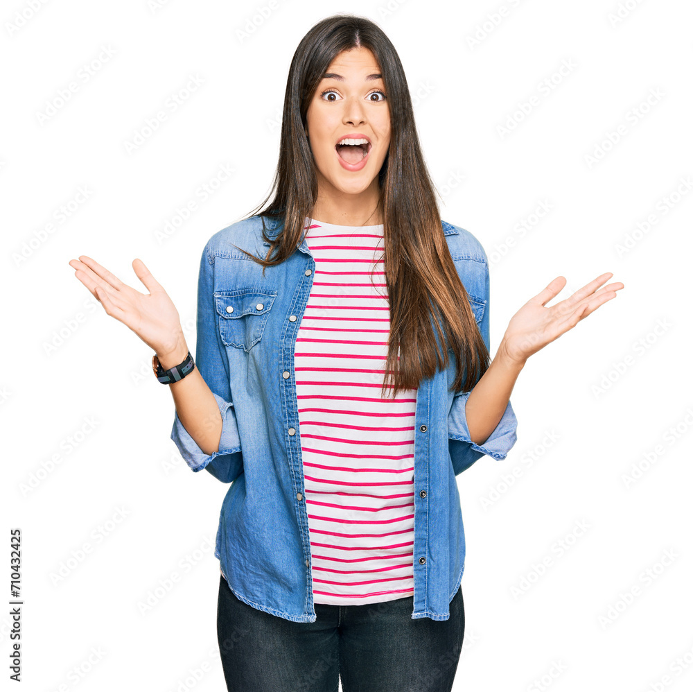 Young brunette woman wearing casual clothes celebrating crazy and amazed for success with arms raised and open eyes screaming excited. winner concept Young brunette woman wearing casual clothes celebrating crazy and amazed for success with arms raised and open eyes screaming excited. winner concept