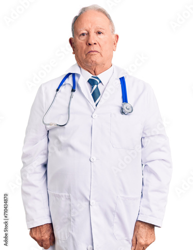 Senior handsome grey-haired man wearing doctor coat and stethoscope relaxed with serious expression on face. simple and natural looking at the camera.