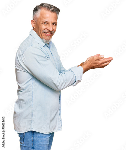 Middle age grey-haired man wearing casual clothes pointing aside with hands open palms showing copy space, presenting advertisement smiling excited happy