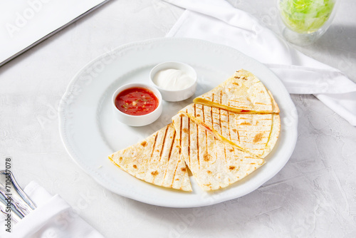 Cheese quesadilla with red and white sauce on a plate