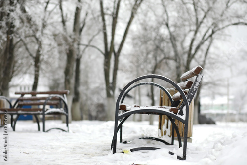 park bench on a winter alley at snowfall. bench with snow after snowstorm or in snow calamity in europe