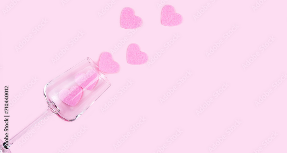 Fototapeta premium Creative flatlay composition with pink hearts and wineglass on the pink background. Valentine's day concept. Top view. Copy space. Selective focus.