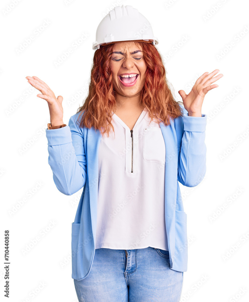 Young latin woman wearing architect hardhat celebrating mad and crazy for success with arms raised and closed eyes screaming excited. winner concept