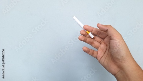 Hand holding a cigarette. No smoking concept. Isolated in gray background.