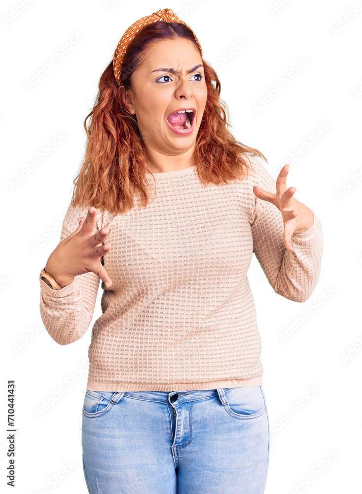 Young latin woman wearing casual clothes and diadem crazy and mad shouting and yelling with aggressive expression and arms raised. frustration concept. Young latin woman wearing casual clothes and diadem crazy and mad shouting and yelling with aggressive expression and arms raised. frustration concept.