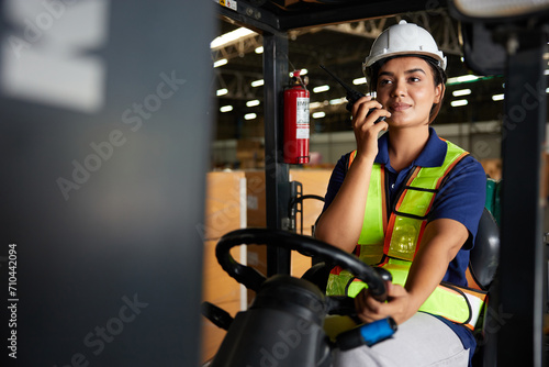 Indian worker driving a forklift and using walkie talkie in warehouse storage