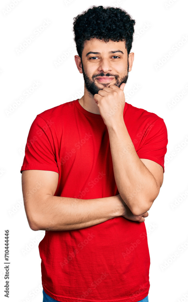 Young arab man with beard wearing casual red t shirt looking confident at the camera with smile with crossed arms and hand raised on chin. thinking positive. Young arab man with beard wearing casual red t shirt looking confident at the camera with smile with crossed arms and hand raised on chin. thinking positive.
