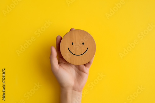 hand holding a wooden seeded circle on a yellow background