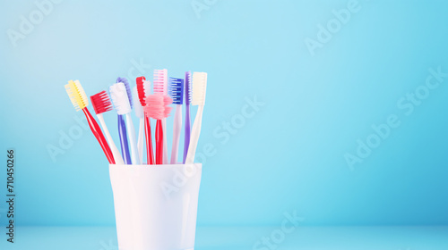 Different toothbrushes in holder on light blue background © Anas