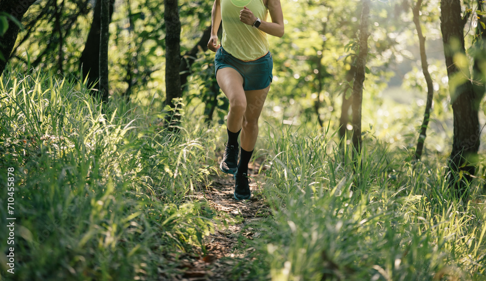 Woman trail runner running at tropical forest mountain peak Woman trail runner running at tropical forest mountain peak