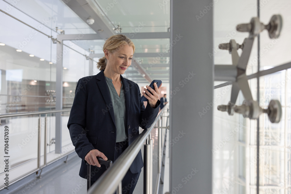 Businesswoman using smartphone in airport terminal Businesswoman using smartphone in airport terminal