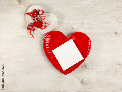 Heart shaped plates, paper card, heart pillows on white wooden background. Top view.