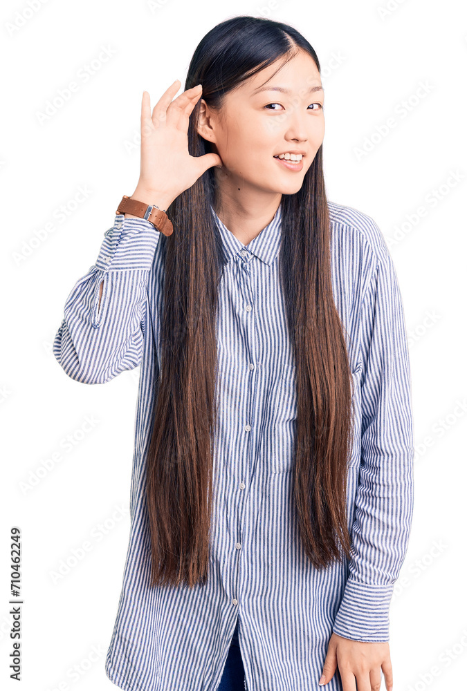 Young beautiful chinese woman wearing casual shirt smiling with hand over ear listening an hearing to rumor or gossip. deafness concept. Young beautiful chinese woman wearing casual shirt smiling with hand over ear listening an hearing to rumor or gossip. deafness concept.