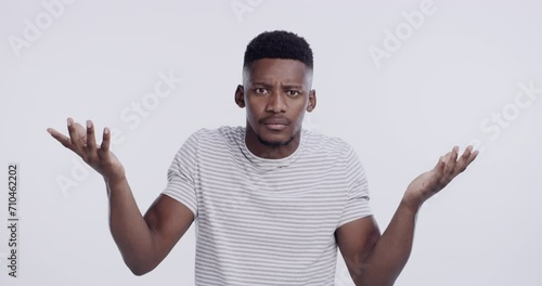 Face, man and shrug in studio for confused questions, forgot why or asking comparison on white background. Portrait, unsure african model or dont know emoji of doubt, choice or palm scale of decision photo