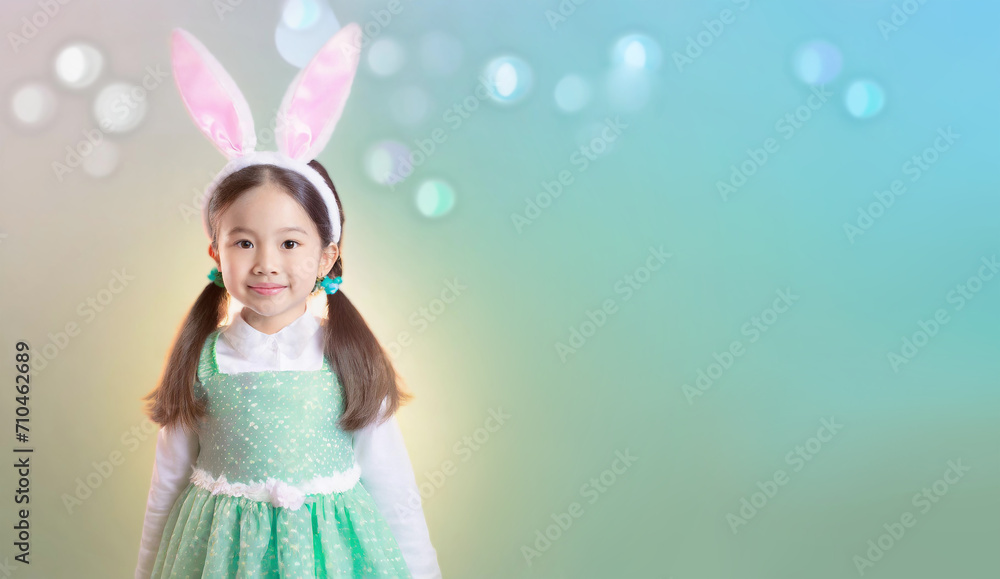 Asian little girl wearing bunny ears on colorful background with bokeh, blank space for text Asian little girl wearing bunny ears on colorful background with bokeh, blank space for text