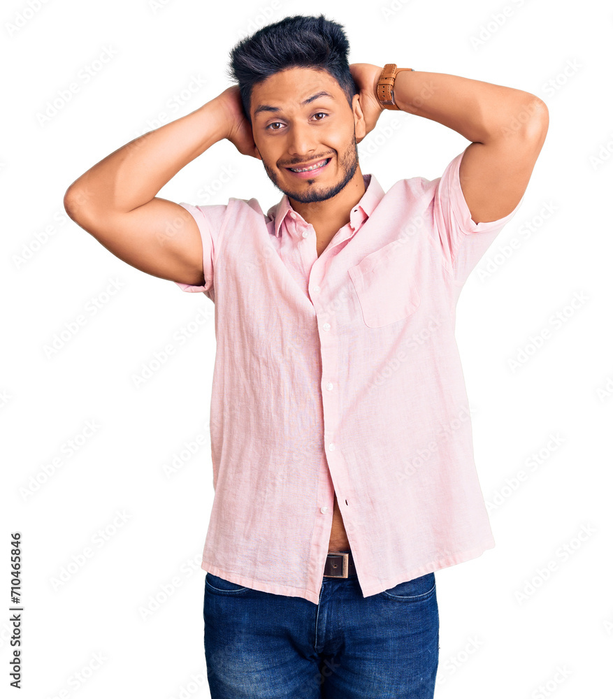Handsome latin american young man wearing casual summer shirt relaxing and stretching, arms and hands behind head and neck smiling happy Handsome latin american young man wearing casual summer shirt relaxing and stretching, arms and hands behind head and neck smiling happy