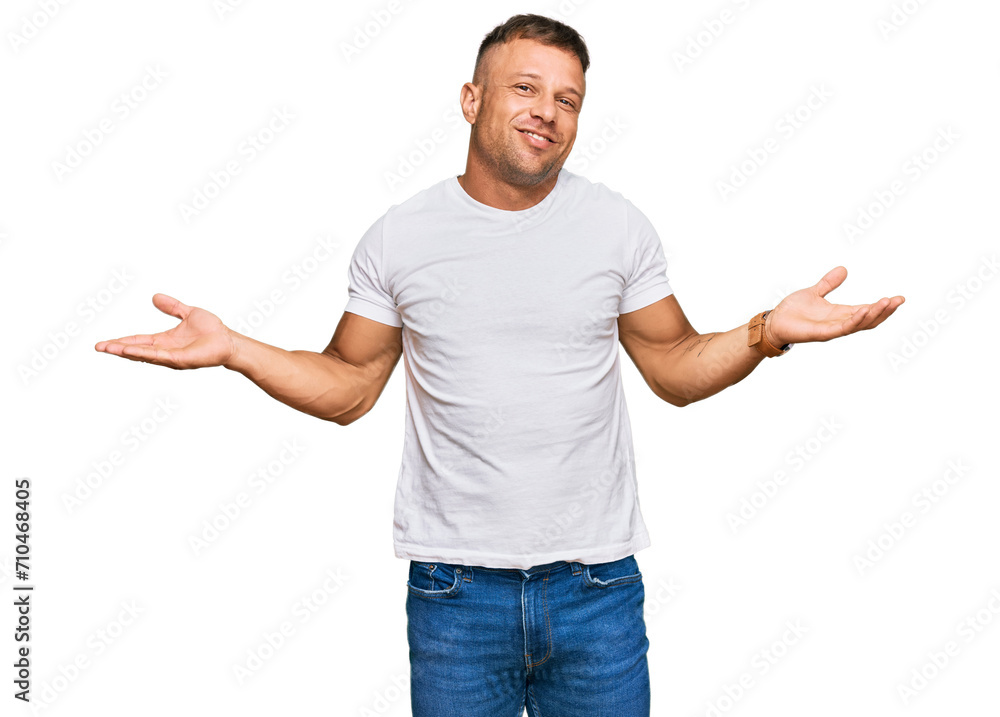 Handsome muscle man wearing casual white tshirt smiling showing both hands open palms, presenting and advertising comparison and balance Handsome muscle man wearing casual white tshirt smiling showing both hands open palms, presenting and advertising comparison and balance
