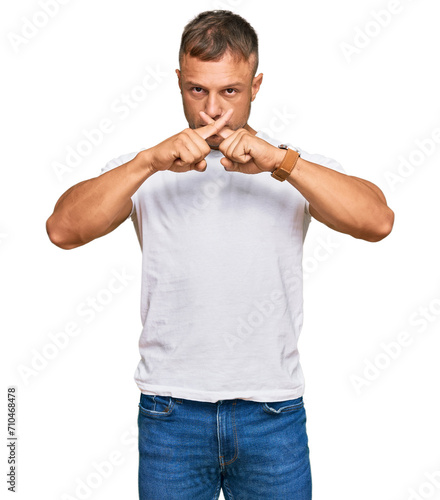 Handsome muscle man wearing casual white tshirt rejection expression crossing fingers doing negative sign