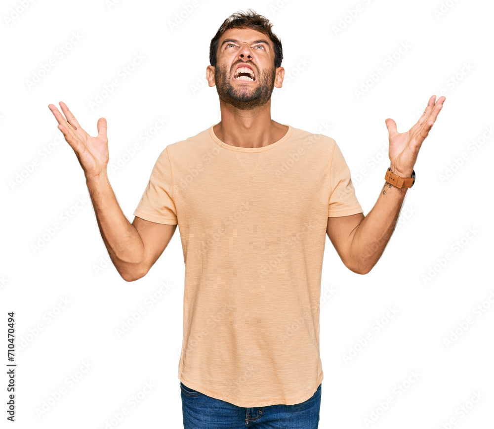 Handsome young man with beard wearing casual tshirt crazy and mad shouting and yelling with aggressive expression and arms raised. frustration concept. Handsome young man with beard wearing casual tshirt crazy and mad shouting and yelling with aggressive expression and arms raised. frustration concept.