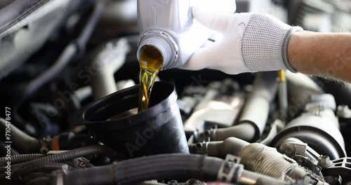 Locksmith pours car engine oil. Oil change in car concept photo