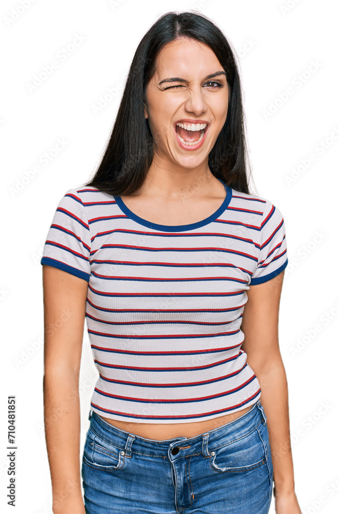 Young hispanic girl wearing casual striped t shirt winking looking at the camera with sexy expression, cheerful and happy face. Young hispanic girl wearing casual striped t shirt winking looking at the camera with sexy expression, cheerful and happy face.