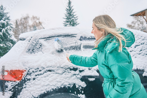 Woman remove her car from snow, Clean car window in winter from snow emoving snow from car windshield. Scraping ice. Winter season car window cleaning. photo