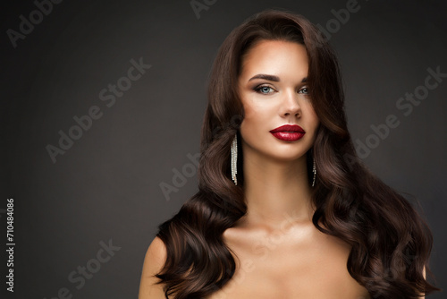 Beautiful Woman Face with Full Red Lips Makeup. Fashion Model Portrait with Wavy Hairstyle over dark Background. Beauty Girl with Brown Long Hair