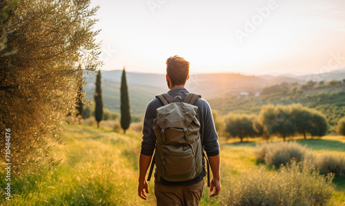 Male hiker traveling, walking alone Italian Tuscan Landscape view under sunset light. Man traveler enjoys with backpack hiking in mountains. Travel, adventure, relax, recharge concept. 