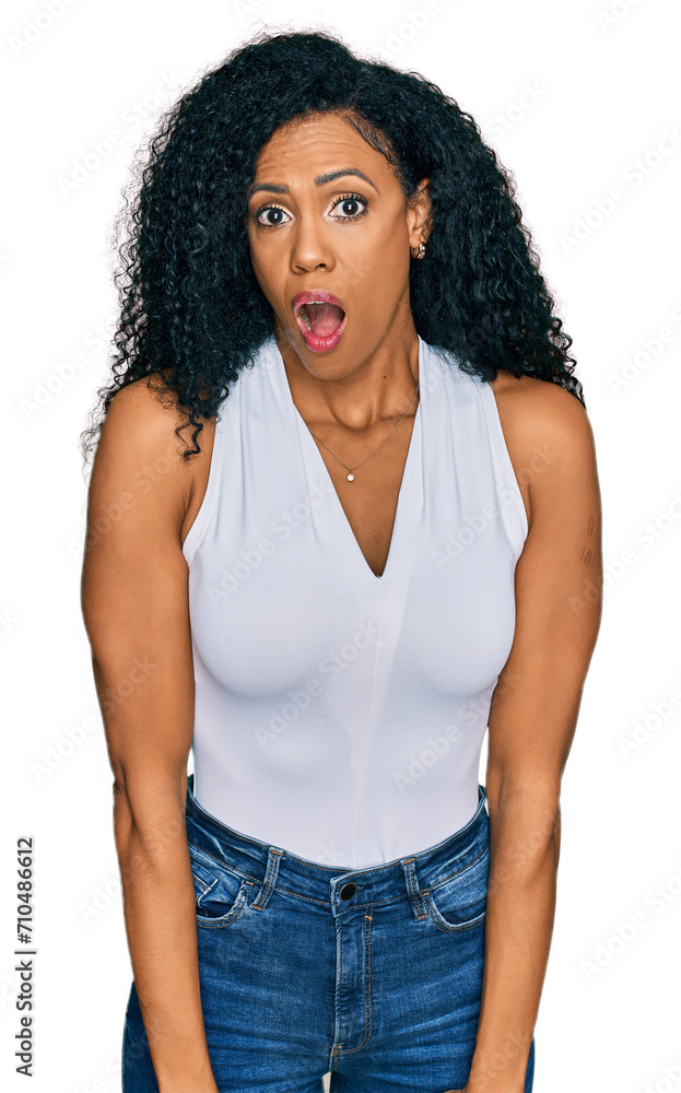 Middle age african american woman wearing casual style with sleeveless shirt afraid and shocked with surprise expression, fear and excited face. Middle age african american woman wearing casual style with sleeveless shirt afraid and shocked with surprise expression, fear and excited face.