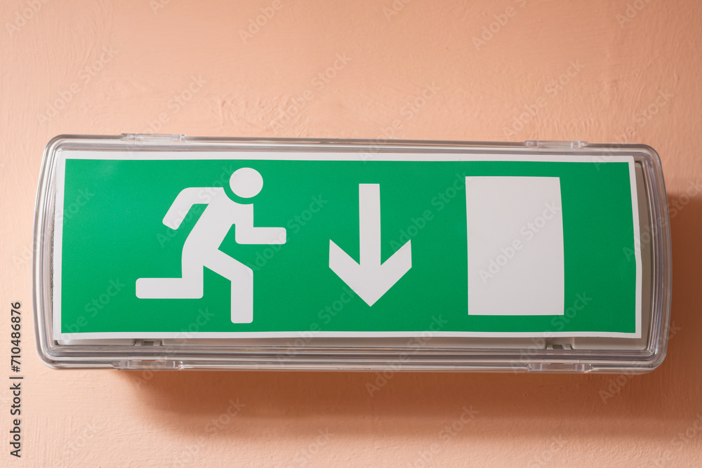 Close-up of a lamp with an evacuation sign on the wall indoors. Close-up of a lamp with an evacuation sign on the wall indoors.