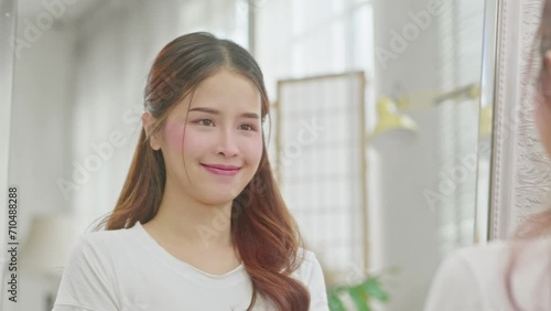 Beautiful Asian young woman gazes at the mirror, exuding pride and confidence, a reflection of self-assurance and empowerment in her own beauty and strength. Self Confidence Concept photo