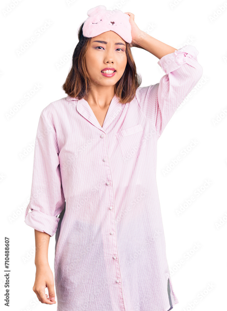 Young beautiful chinese girl wearing sleep mask and pajama confuse and wonder about question. uncertain with doubt, thinking with hand on head. pensive concept. Young beautiful chinese girl wearing sleep mask and pajama confuse and wonder about question. uncertain with doubt, thinking with hand on head. pensive concept.