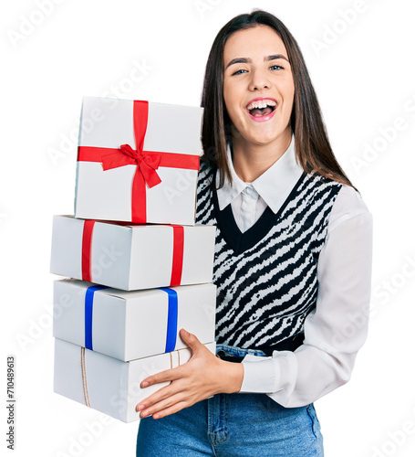 Young brunette teenager holding gifts smiling and laughing hard out loud because funny crazy joke.