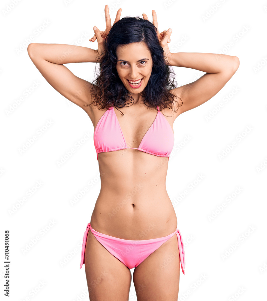 Young beautiful hispanic woman wearing bikini posing funny and crazy with fingers on head as bunny ears, smiling cheerful Young beautiful hispanic woman wearing bikini posing funny and crazy with fingers on head as bunny ears, smiling cheerful