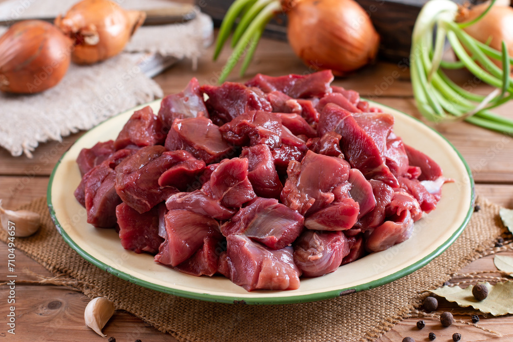 Raw chopped beef meat on a board. Raw organic meat beef or lamb, spices, herbs. Goulash. Raw uncooked meat. Meat with blood.