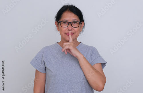 Asian woman in her casual attire gesturing not to make any noise photo