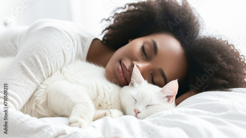 Young African American woman sleeping together with a white cat. 