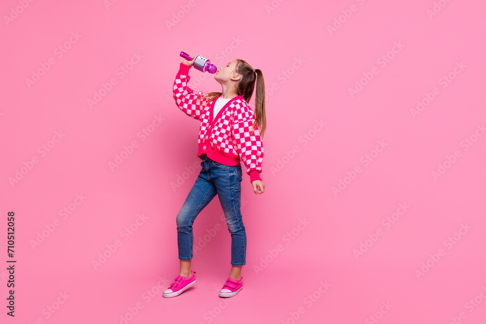 Full size photo of lovely girl with tails dressed knit cardigan jeans sing song in mic look empty space isolated on pink color background Full size photo of lovely girl with tails dressed knit cardigan jeans sing song in mic look empty space isolated on pink color background