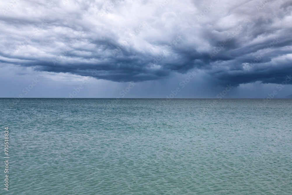 Dramatic dark blue storm clouds and rain over the sea. Black Sea.