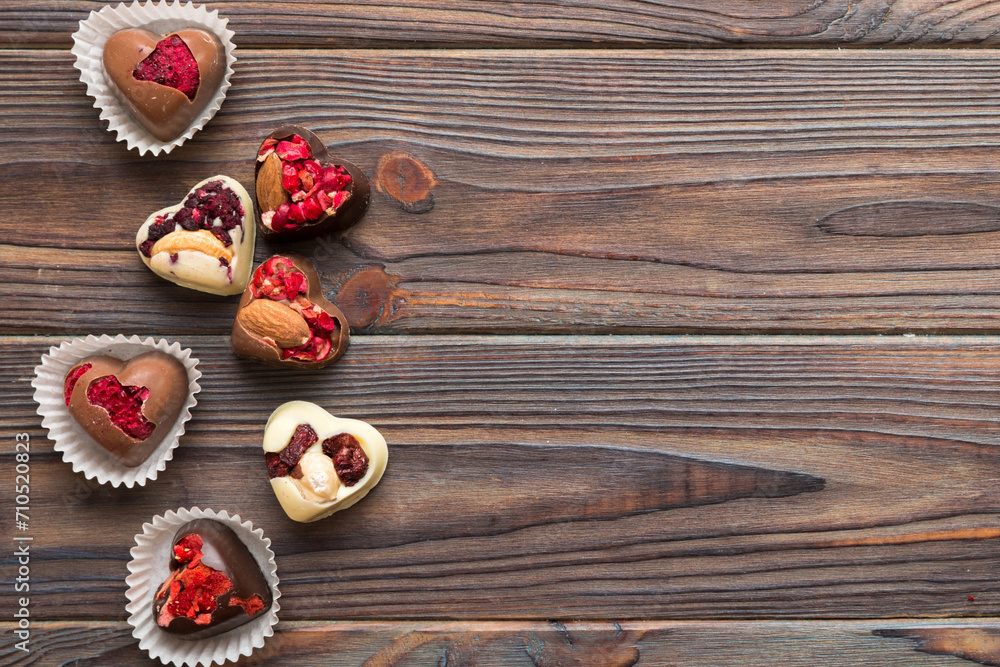 chocolate sweets in the form of a heart with fruits and nuts on a colored background. top view with space for text, holiday concept chocolate sweets in the form of a heart with fruits and nuts on a colored background. top view with space for text, holiday concept