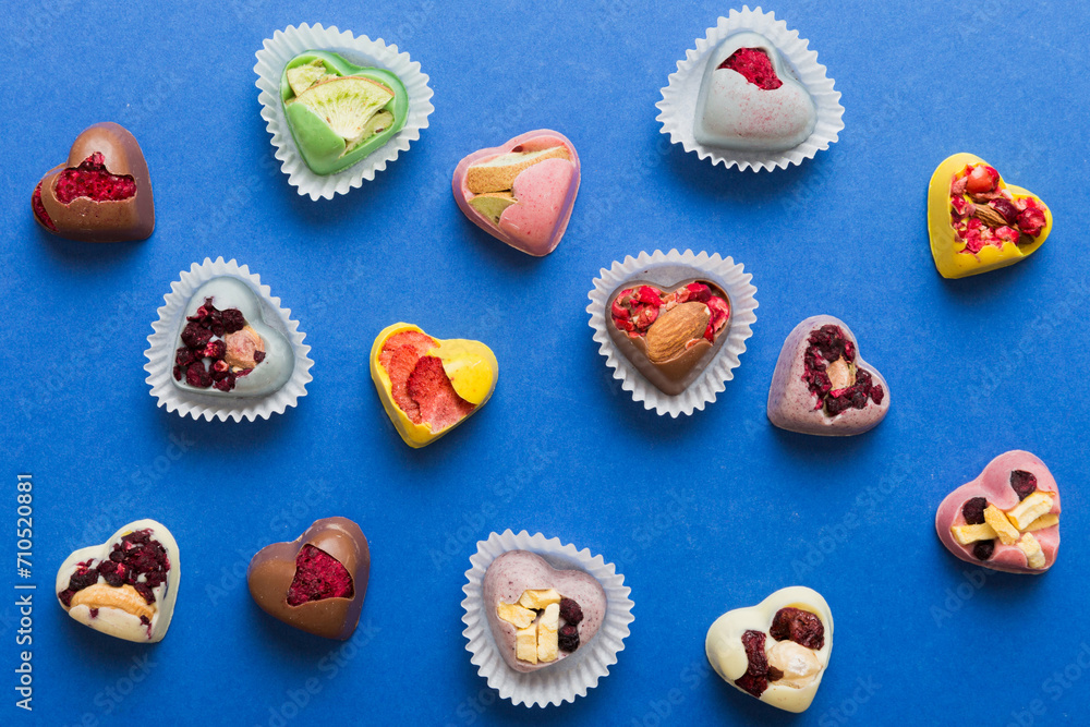 chocolate sweets in the form of a heart with fruits and nuts on a colored background. top view with space for text, holiday concept chocolate sweets in the form of a heart with fruits and nuts on a colored background. top view with space for text, holiday concept