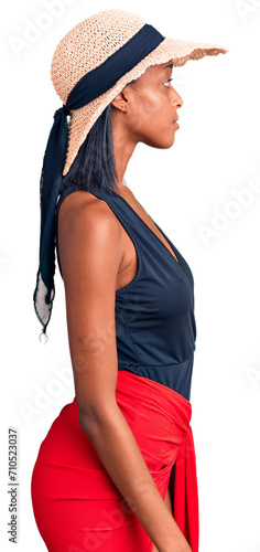 Young african american woman wearing swimsuit and summer hat looking to side, relax profile pose with natural face and confident smile.