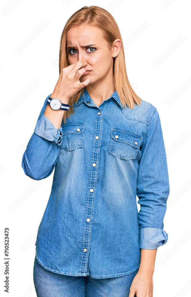 Beautiful caucasian woman wearing casual denim jacket smelling something stinky and disgusting, intolerable smell, holding breath with fingers on nose. bad smell Beautiful caucasian woman wearing casual denim jacket smelling something stinky and disgusting, intolerable smell, holding breath with fingers on nose. bad smell