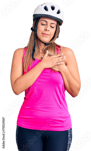 Young beautiful woman wearing bike helmet smiling with hands on chest with closed eyes and grateful gesture on face. health concept. © Krakenimages.com