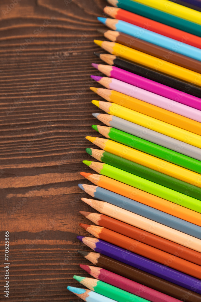 Obraz premium Set of watercolor pencils on brown wooden. Top view