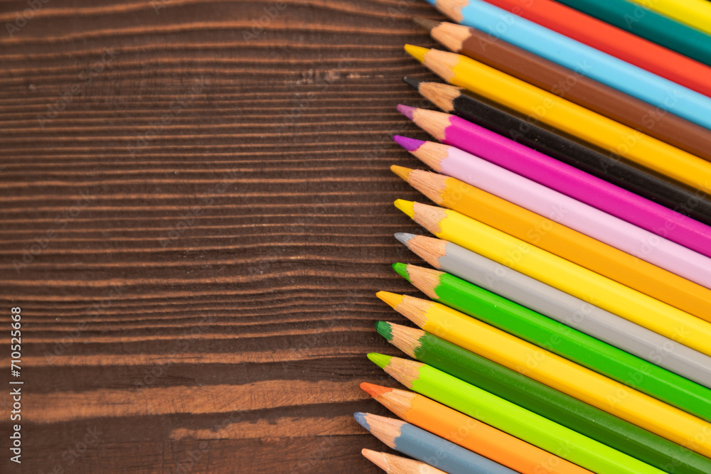 Obraz premium Set of watercolor pencils on brown wooden. Top view, copy space